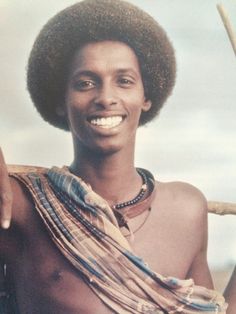 a man with an afro holding a stick in his hand and smiling at the camera