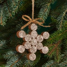 a christmas ornament hanging from a pine tree with glittered circles on it