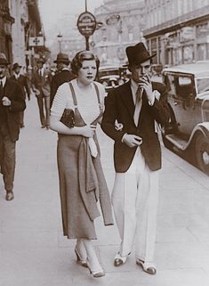 an old black and white photo of two people walking down the street