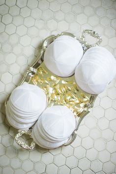 four white balls are sitting on a silver tray with gold foil around them and one is in the shape of a ball