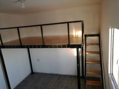 an empty room with a loft bed next to a window and stairs leading up to the second floor