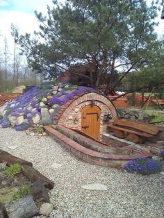 an outdoor area with benches and a stone fire pit in the middle, surrounded by lavender flowers