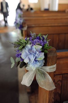 a bouquet of flowers sitting on top of a wooden bench in front of pews