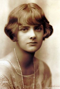 an old black and white photo of a woman with pearls on her neck, looking at the camera