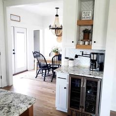 a kitchen with white cabinets and marble counter tops, black chairs and a chandelier hanging from the ceiling