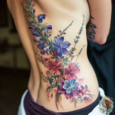 a woman's stomach with flowers and leaves on her side, as well as the bottom part of her lower back