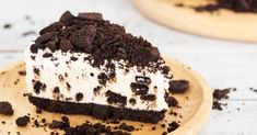 a piece of cake with oreo cookies and cream frosting sitting on a wooden plate