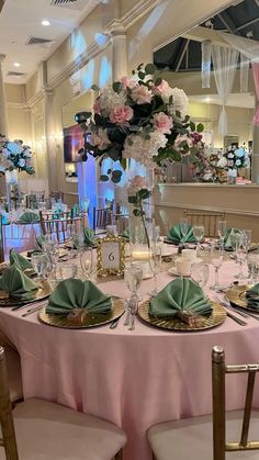 the table is set with pink and green plates, silverware, and flowers in vases