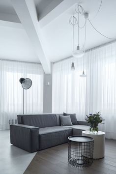 a living room with a gray couch and white curtains