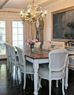 a dining room table with white chairs and a chalkboard on the wall behind it