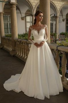 a woman wearing a wedding dress standing in front of a building with columns and pillars