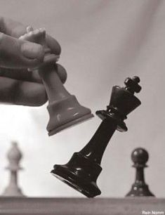 a hand holding a chess piece over the top of a chess board