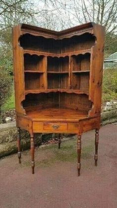 an old wooden bookcase with drawers on the front and bottom, sitting in a driveway