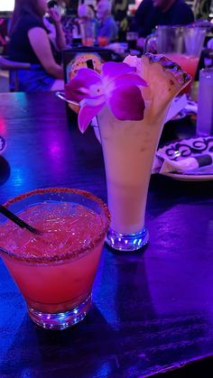 two cocktails on a bar with purple lighting