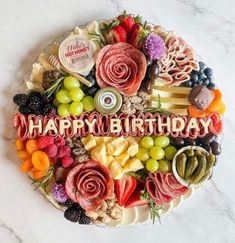 a birthday cake with the words happy birthday surrounded by fruits, nuts and cheeses