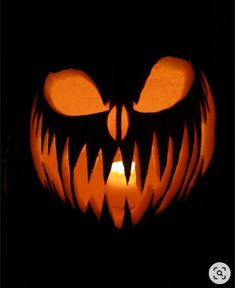 a carved pumpkin with an evil face on it's face, lit up in the dark