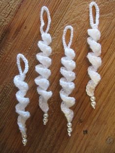 three white crocheted hair clips sitting on top of a wooden table