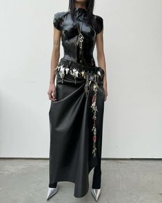 a woman wearing a black leather outfit with silver shoes and a skirt that has flowers on it