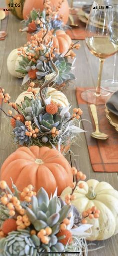 the table is set with pumpkins and succulents