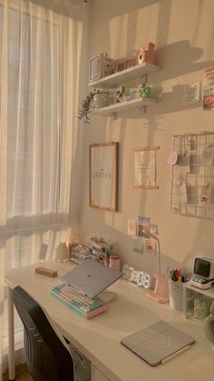 a white desk topped with a laptop computer next to a window covered in sheer curtains