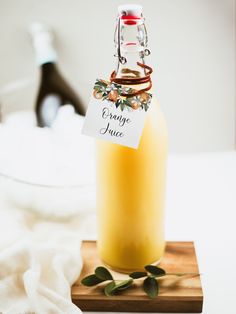 a bottle of orange juice sitting on top of a wooden cutting board