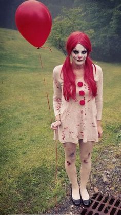 a woman with red hair and makeup is holding a balloon in her hand while standing on the ground