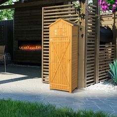 a tall wooden shed sitting in the middle of a yard next to a fire place