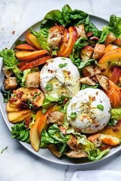 a white plate topped with lettuce, peaches and eggs