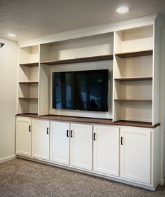 an entertainment center with white cabinets and a flat screen tv mounted on it's wall