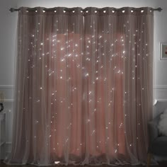 a curtain with white lights on it in front of a couch and window sill