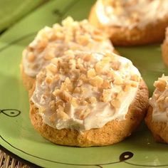 three cookies with white frosting on a green plate