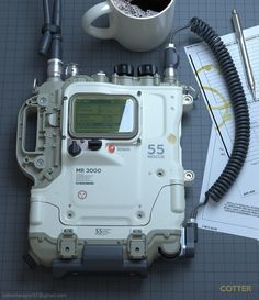 an electronic device sitting on top of a table next to a coffee cup and pen