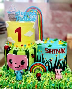 a birthday cake is decorated with animals and rainbows