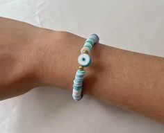 This bracelet has a blue clay evil eye charm and is made out of blue and white clay beads. To avoid damage, store this bracelet in a dry and cool environment when not in use. Handmade Blue Evil Eye Bracelet Casual Style, Blue Beaded Bracelets With Evil Eye, Adjustable Blue Evil Eye Bracelet Hand-strung, Adjustable Turquoise Beaded Bracelets With Evil Eye, Adjustable Blue Hand-strung Evil Eye Bracelet, Adjustable Blue Evil Eye Bracelet With Colorful Beads, Blue Evil Eye Beaded Bracelets For Beach, Blue Beaded Evil Eye Bracelets For The Beach, Blue Evil Eye Round Beaded Bracelets