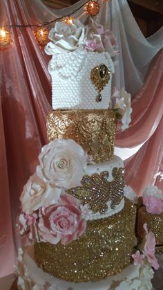 a three tiered wedding cake decorated with flowers and gold sequins on a table