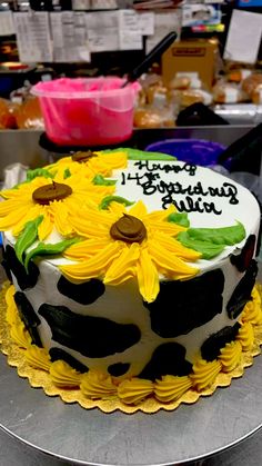 a cake decorated with sunflowers on top of a metal tray in a bakery