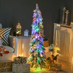 a lit christmas tree sitting on top of a wooden floor next to boxes and presents