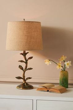 a table with a lamp, book and flowers on it