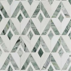 a white and green tiled wall with diamond shaped tiles on the bottom, in an irregular pattern