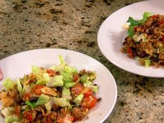 two white plates filled with food sitting on top of a granite countertop next to each other