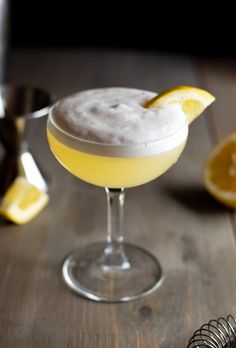 a glass filled with a drink sitting on top of a table next to an orange slice