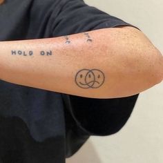 a man with a tattoo on his arm that reads hold on and has two smiley faces