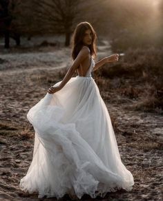 a woman in a white dress is standing on the ground with her arms out and pointing at something