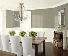 a dining room table with white chairs and green flowers in vases on the top