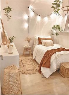 a bedroom with white walls and wooden floors has plants on the wall above the bed