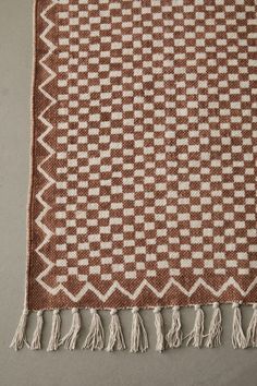 a brown and white checkered rug with fringes