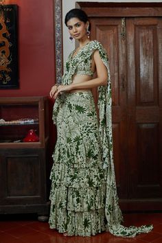 Sand tiered pre-draped saree with green garden print print all-over. Comes with sleeveless pleated blouse.
Component: 2
Pattern: Print
Type Of Work: Garden Print
Neckline: V neck
Sleeve Type: Sleeveless
Fabric: Georgette
Color: Beige
Other Details: 
Pleated blouse
Tiered silhouette
Closure: Back hook
Occasion: Destination Wedding - Aza Fashions Green Bohemian Pre-draped Saree For Wedding, Green Bohemian Fitted Pre-draped Saree, Green Fitted Bohemian Pre-draped Saree, Beige Garden, Arpita Mehta, Draped Saree, Ruffle Saree, Drape Saree, Pleated Blouse