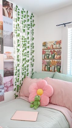 a pink flower sitting on top of a bed next to a green teddy bear and pillows