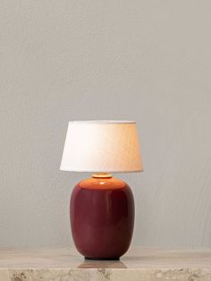 a red lamp sitting on top of a table next to a white wall and floor