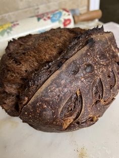 a piece of chocolate cake sitting on top of a white counter next to a roll of toilet paper